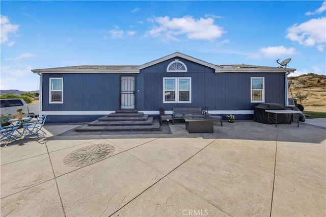 view of front of house featuring a patio and an outdoor living space with a fire pit