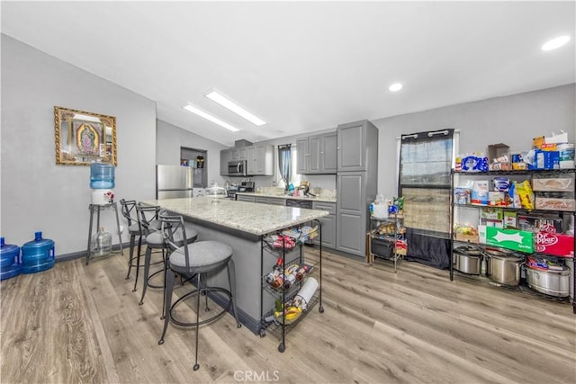 kitchen with gray cabinetry, stainless steel appliances, lofted ceiling, and light wood-type flooring