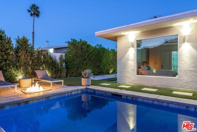 pool at dusk with an outdoor fire pit