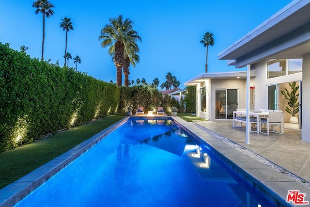 pool at dusk featuring a patio area