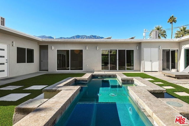 rear view of property featuring a mountain view and a swimming pool with hot tub