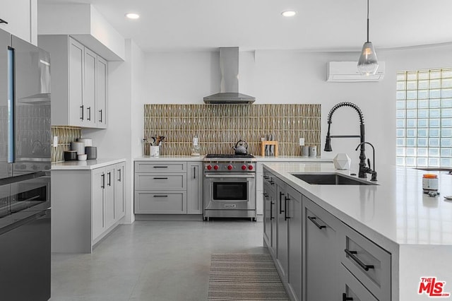 kitchen with decorative backsplash, wall chimney exhaust hood, sink, premium stove, and hanging light fixtures