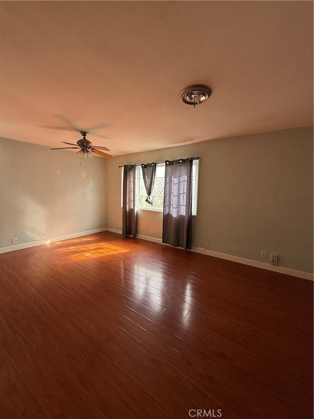 empty room with dark wood-type flooring and ceiling fan