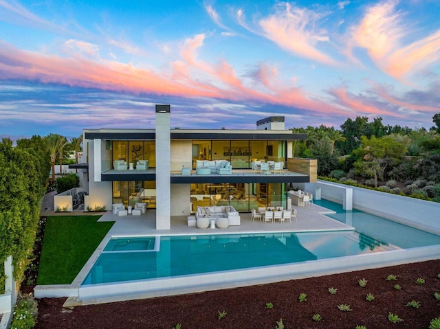 back house at dusk featuring outdoor lounge area and a patio area