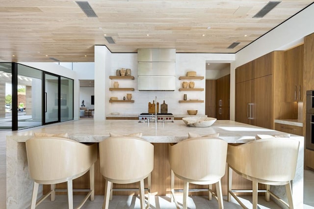 kitchen with wooden ceiling, a kitchen bar, a wall of windows, and white cabinetry