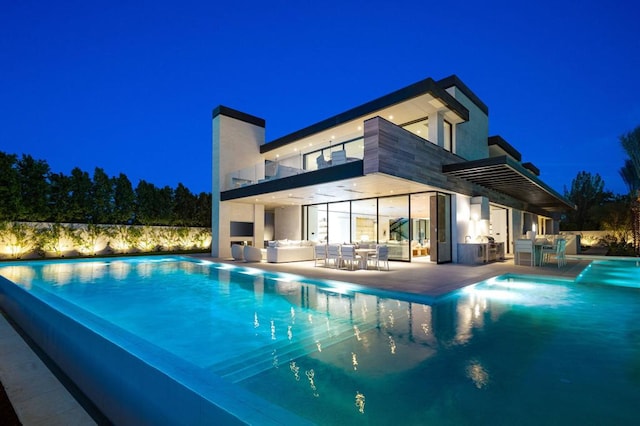 pool at twilight featuring a patio and an outdoor kitchen