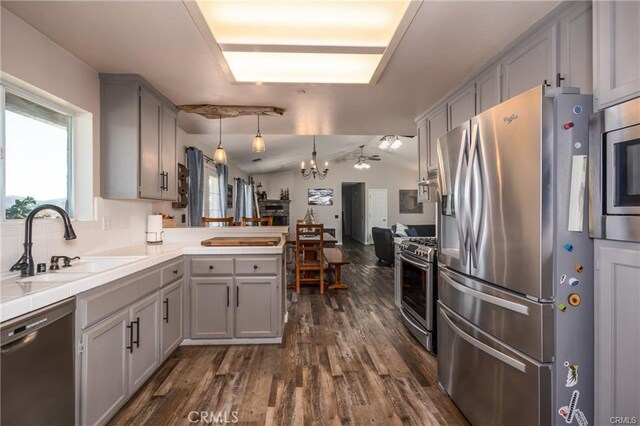 kitchen featuring gray cabinets, vaulted ceiling, sink, stainless steel appliances, and kitchen peninsula