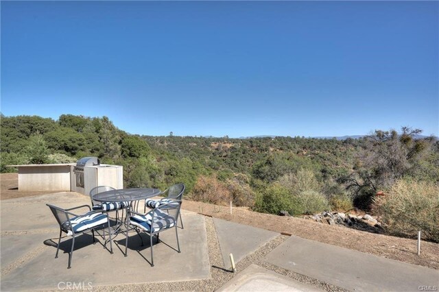 view of patio with a forest view, outdoor dining area, and area for grilling