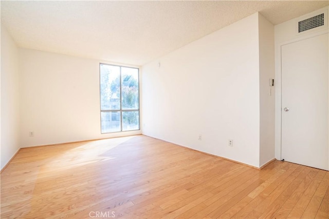 unfurnished room with a textured ceiling and light hardwood / wood-style floors