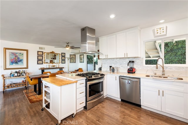 kitchen featuring hardwood / wood-style floors, sink, white cabinets, appliances with stainless steel finishes, and island range hood