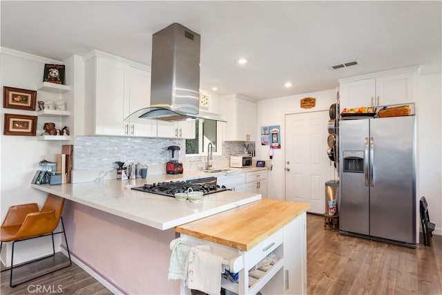 kitchen with island range hood, dark wood-type flooring, stainless steel appliances, and white cabinets