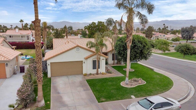 view of front of home featuring a mountain view, a front lawn, and a garage