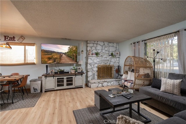 living room featuring light hardwood / wood-style floors, a fireplace, and a textured ceiling