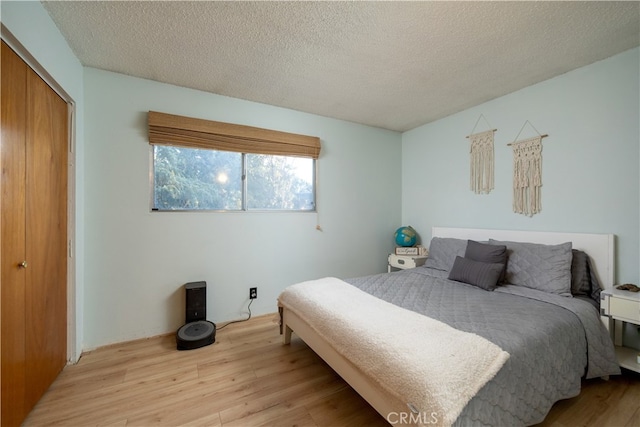 bedroom with a textured ceiling, a closet, and light hardwood / wood-style floors