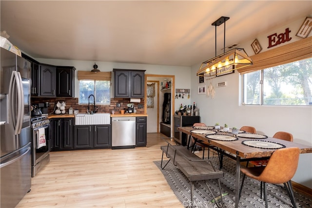 kitchen with pendant lighting, stainless steel appliances, a healthy amount of sunlight, and tasteful backsplash