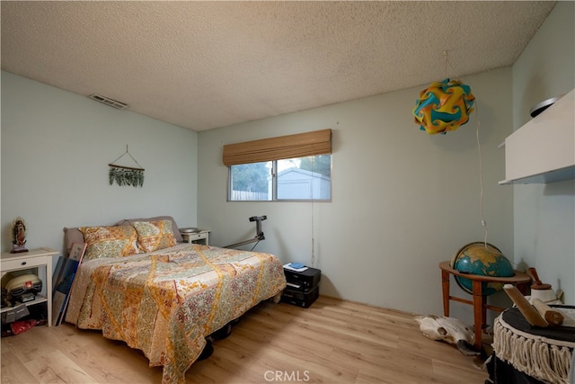 bedroom featuring light hardwood / wood-style flooring and a textured ceiling