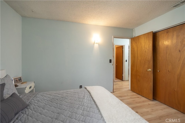 bedroom featuring a textured ceiling, light hardwood / wood-style flooring, and a closet