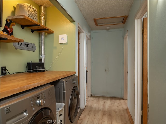 laundry room with washer and clothes dryer, a textured ceiling, and light hardwood / wood-style floors