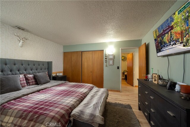 bedroom with a textured ceiling, light hardwood / wood-style flooring, and a closet