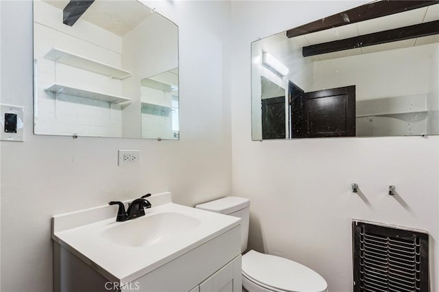 bathroom featuring beamed ceiling, vanity, and toilet