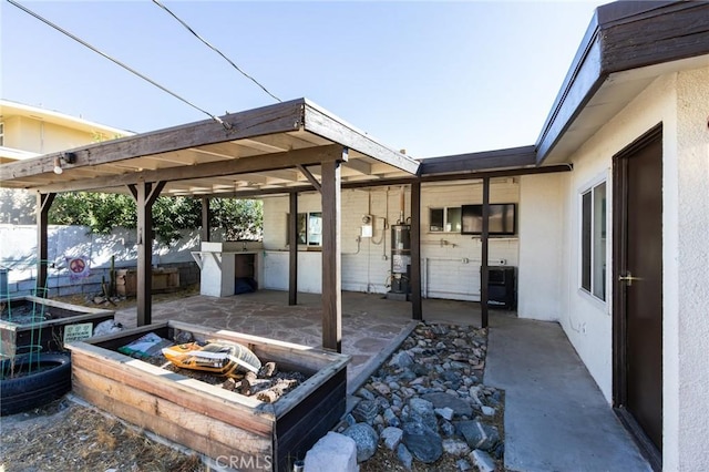 view of patio / terrace featuring an outdoor kitchen, a pergola, and water heater