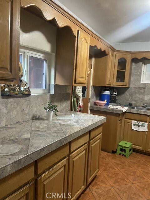 kitchen with light parquet flooring, backsplash, and tile countertops