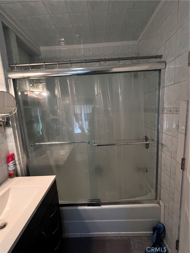 bathroom featuring shower / bath combination with glass door and vanity