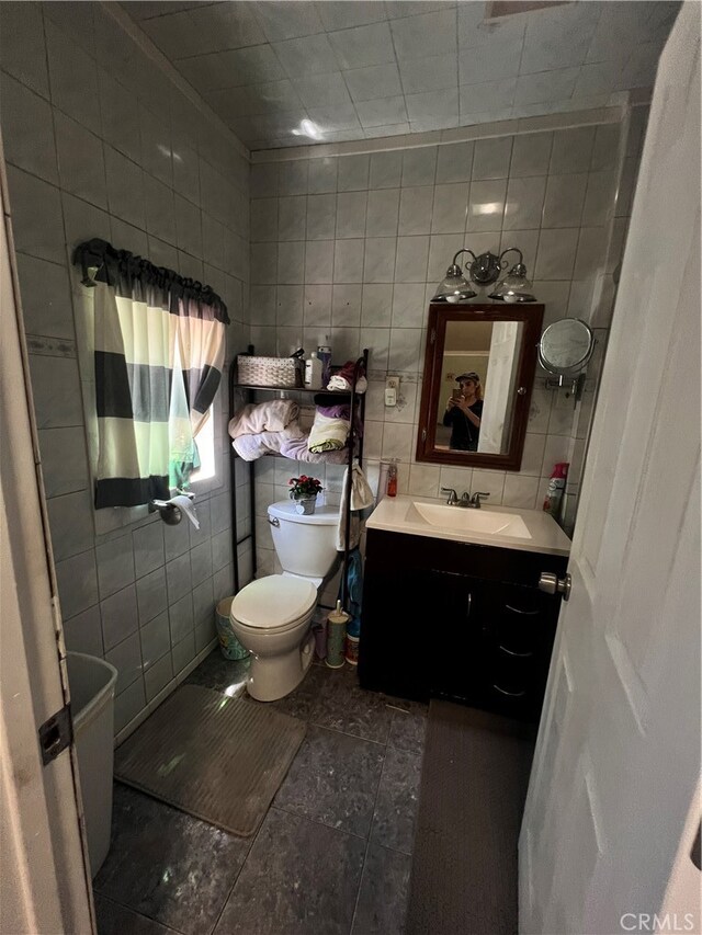 bathroom featuring vanity, tile walls, toilet, and tile patterned floors