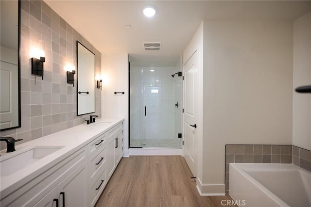 bathroom with hardwood / wood-style flooring, vanity, decorative backsplash, and independent shower and bath