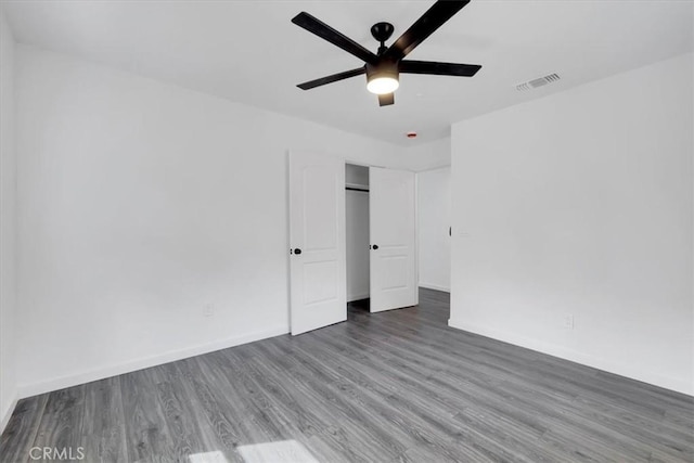 unfurnished bedroom featuring baseboards, visible vents, ceiling fan, wood finished floors, and a closet