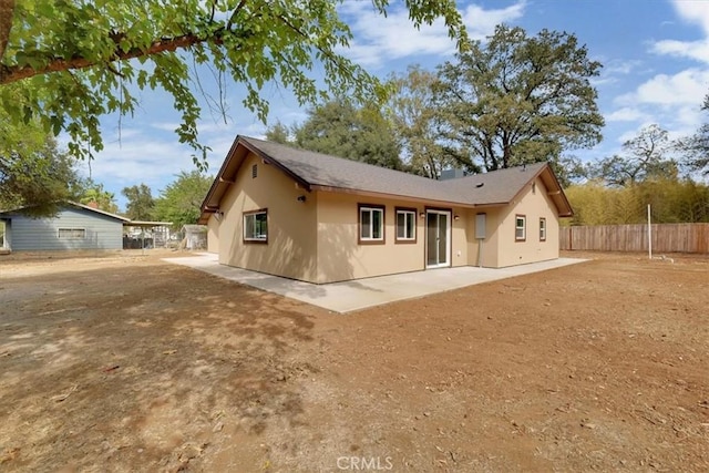 rear view of house with a patio area, fence, and stucco siding