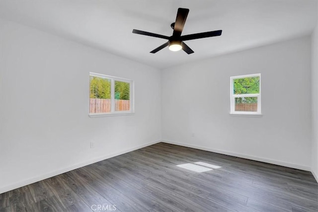 empty room with baseboards, dark wood-style flooring, a ceiling fan, and a healthy amount of sunlight