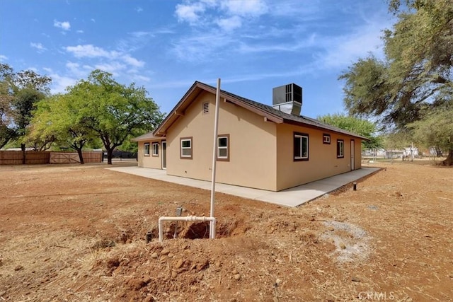 view of side of property with a patio area, fence, central AC, and stucco siding