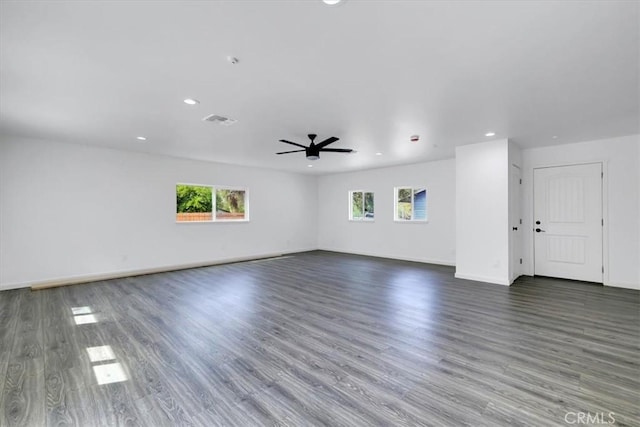 unfurnished living room featuring ceiling fan, dark wood-style flooring, and a wealth of natural light