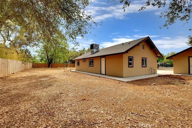 rear view of property featuring cooling unit, a fenced backyard, and stucco siding