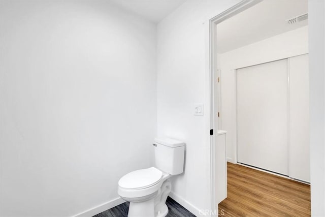 bathroom featuring toilet, wood finished floors, visible vents, and baseboards