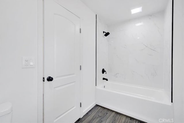 bathroom featuring toilet, wood finished floors, and bathing tub / shower combination