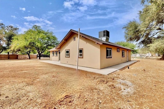 view of property exterior featuring cooling unit, fence, a patio, and stucco siding