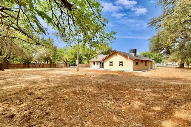 back of property with central AC unit and fence