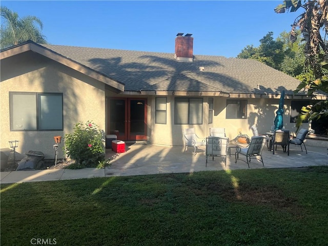 rear view of property featuring french doors, a patio, and a lawn