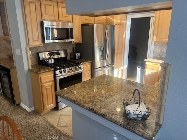 kitchen featuring light tile patterned floors, backsplash, stainless steel appliances, and dark stone counters