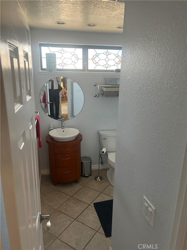 bathroom with tile patterned floors, vanity, a textured ceiling, and toilet