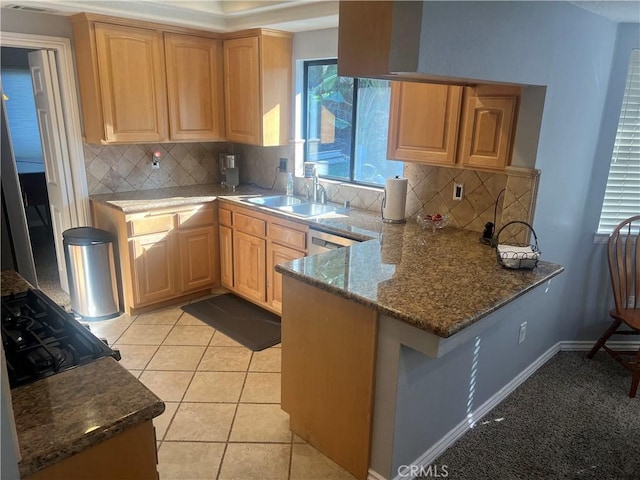 kitchen with decorative backsplash, dark stone countertops, kitchen peninsula, and sink