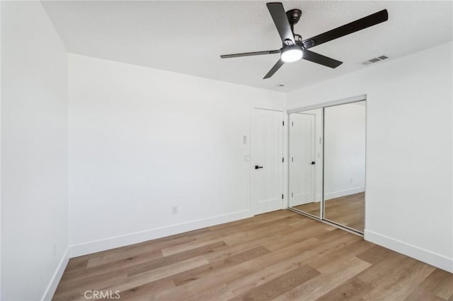 unfurnished bedroom with ceiling fan, light hardwood / wood-style floors, and a closet