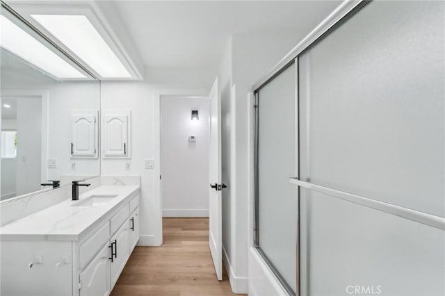 bathroom featuring vanity, hardwood / wood-style flooring, and enclosed tub / shower combo