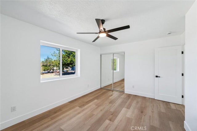 unfurnished bedroom with ceiling fan, multiple windows, a closet, and light hardwood / wood-style flooring