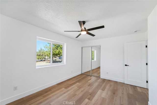 unfurnished bedroom with ceiling fan, a textured ceiling, a closet, and light hardwood / wood-style flooring