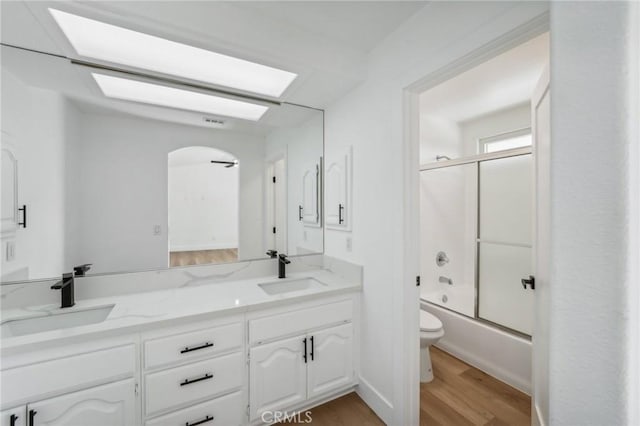 full bathroom with vanity, toilet, bath / shower combo with glass door, and wood-type flooring