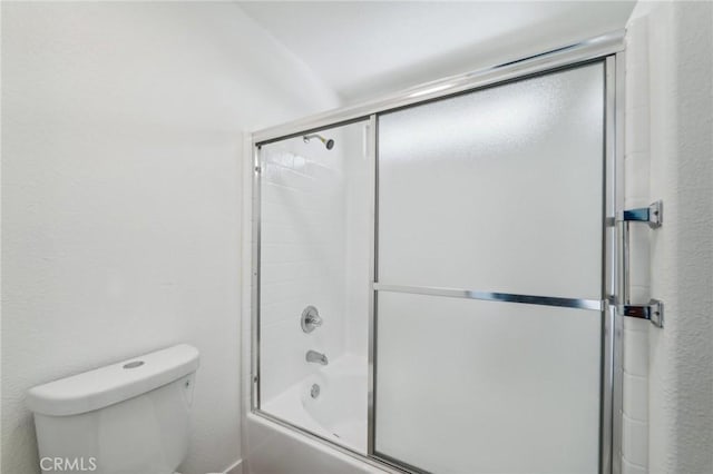 bathroom with toilet and shower / bath combination with glass door