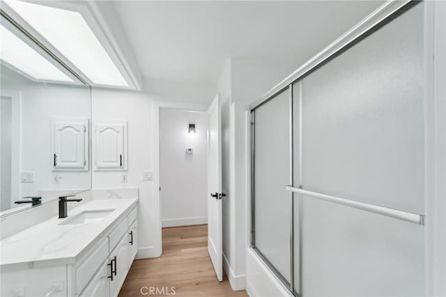 bathroom featuring bath / shower combo with glass door, hardwood / wood-style flooring, and vanity